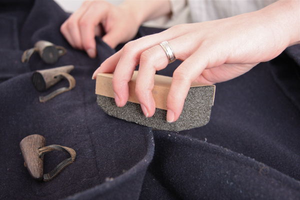 Get rid of lint balls on a coat using a pumice stone